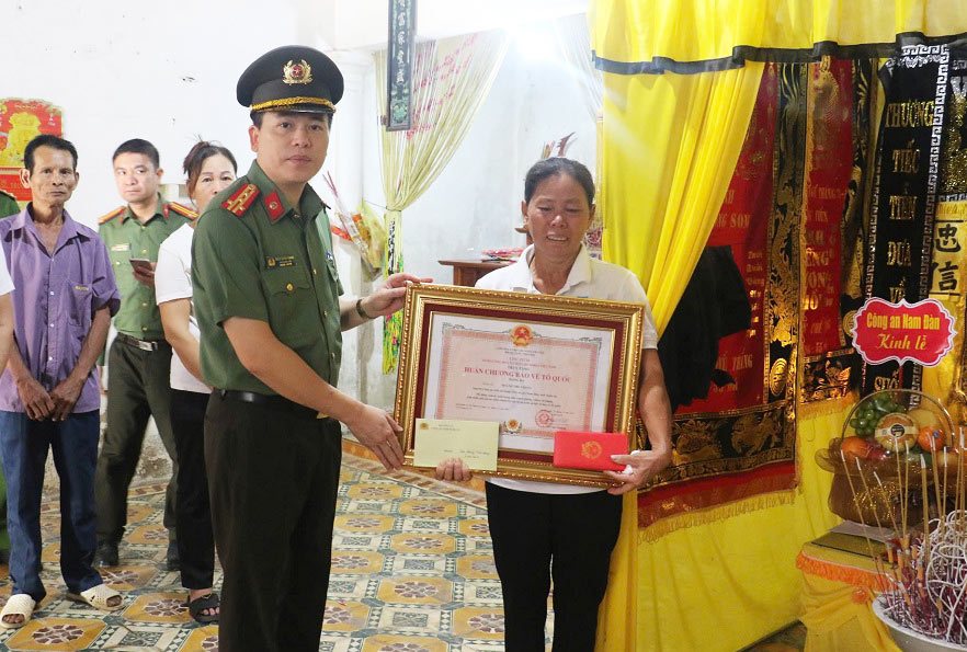 Đại tá Trần Hồng Quang, Phó Bí thư Đảng ủy, Phó Giám đốc Công an tỉnh Nghệ An trao Huân chương Bảo vệ Tổ quốc hạng Ba đến thân nhân ông Hoàng Thế Thắng, nguyên công an viên đã hy sinh. Ảnh: Công an Nghệ An