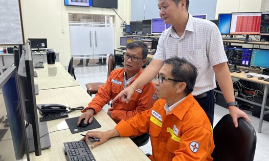 Ông Võ Sỹ Danh (người đứng) hướng dẫn công nhân theo dõi truyền tải điện. Ảnh: Đức Long