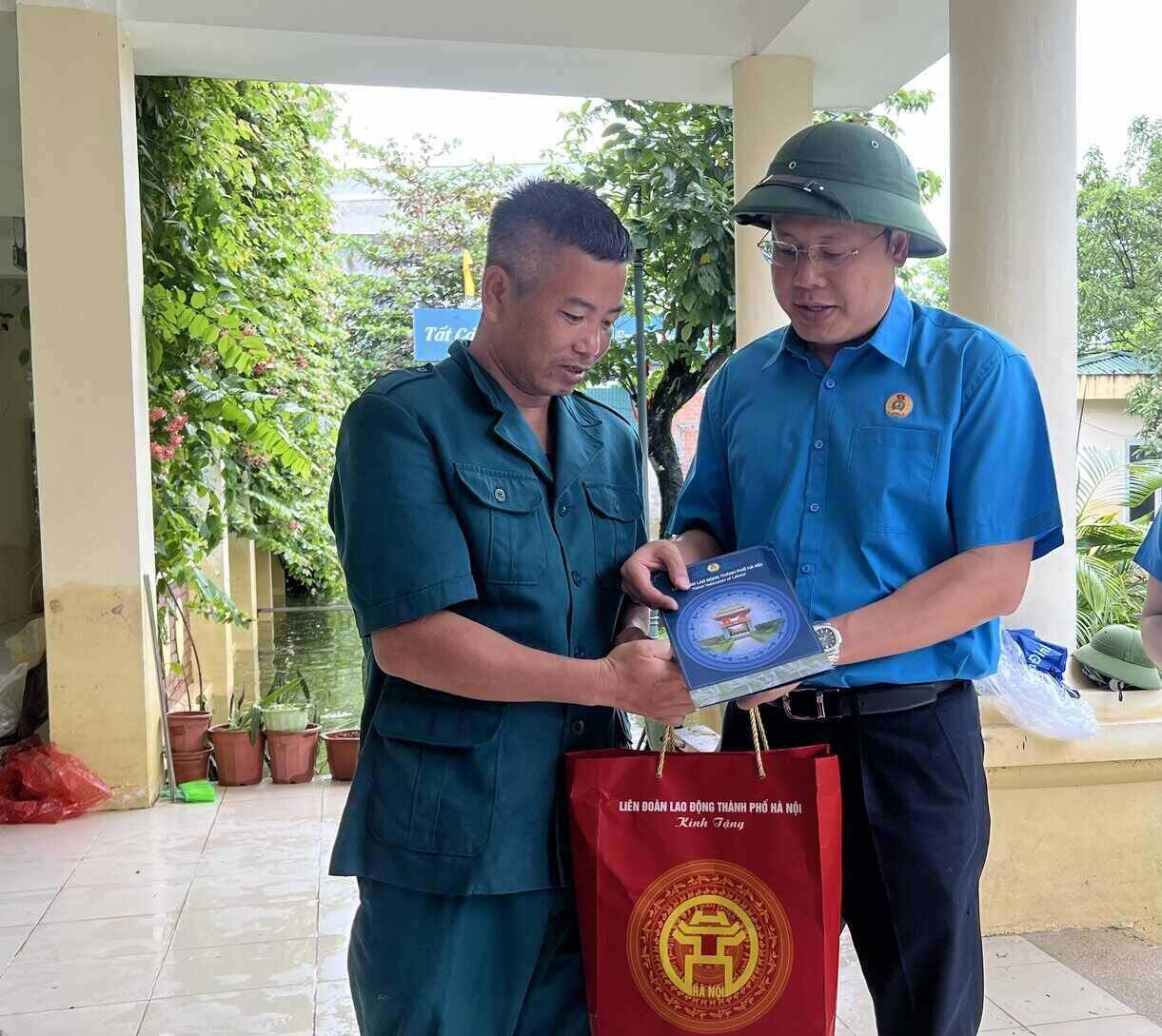 Chủ tịch LĐLĐ Thành phố Hà Nội Phạm Quang Thanh (bên phải) trao hỗ trợ cho ông Hoàng Văn Linh, hiện công tác tại UBND xã Nam Phương Tiến. Ảnh: Kiều Vũ 