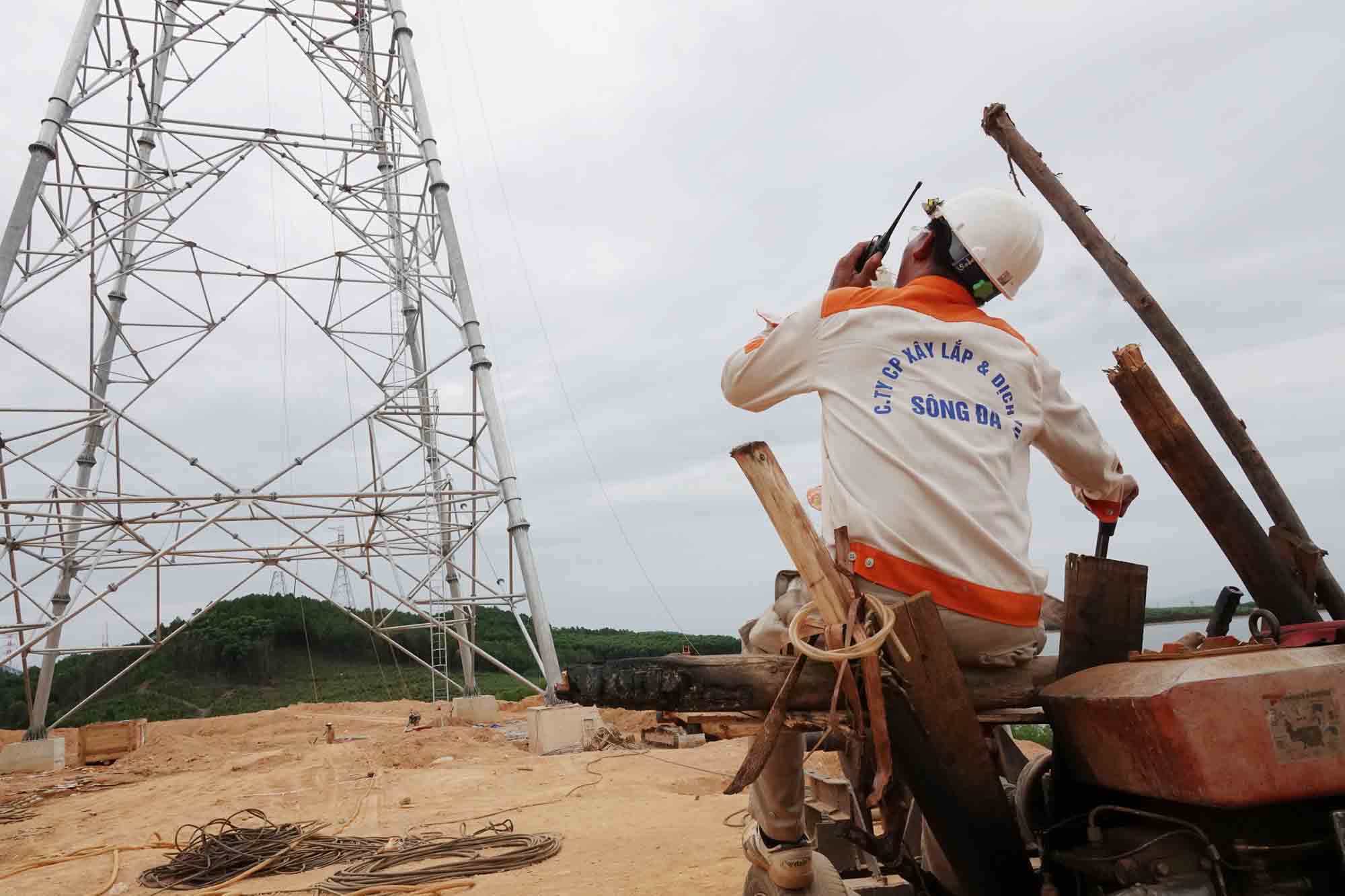 Mr. Quang is listening to the radio directing construction workers on high electric poles. Photo: Tran Tuan.