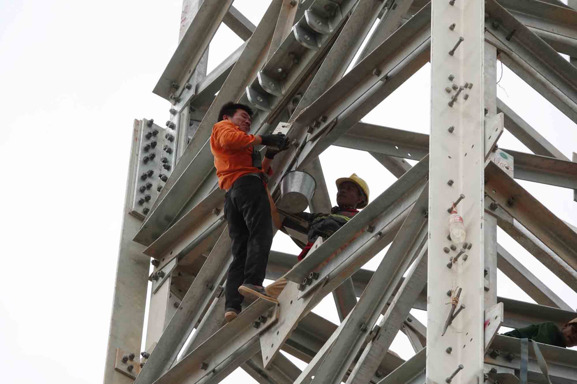 Workers climbing on electric poles are tightening the screws. Photo: Tran Tuan.