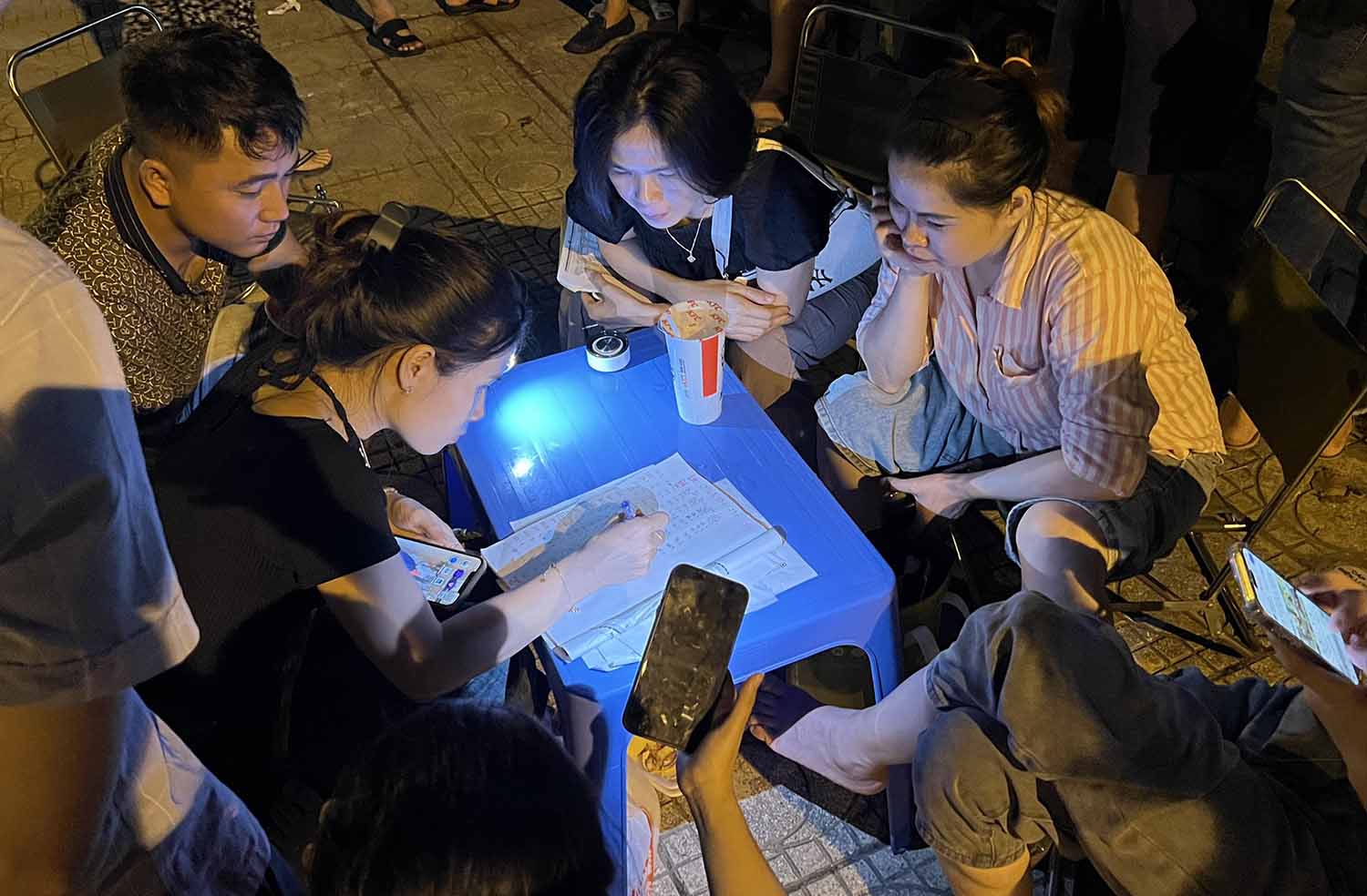 Một nhóm người ngồi tổng hợp kết quả đấu giá đất, bàn phương án bỏ giá như thế nào trong cuộc đấu giá ngày 19.8. Ảnh: Anh Quân