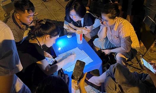 Một nhóm người ngồi tổng hợp kết quả đấu giá đất, bàn phương án bỏ giá như thế nào trong cuộc đấu giá ngày 19.8. Ảnh: Anh Quân