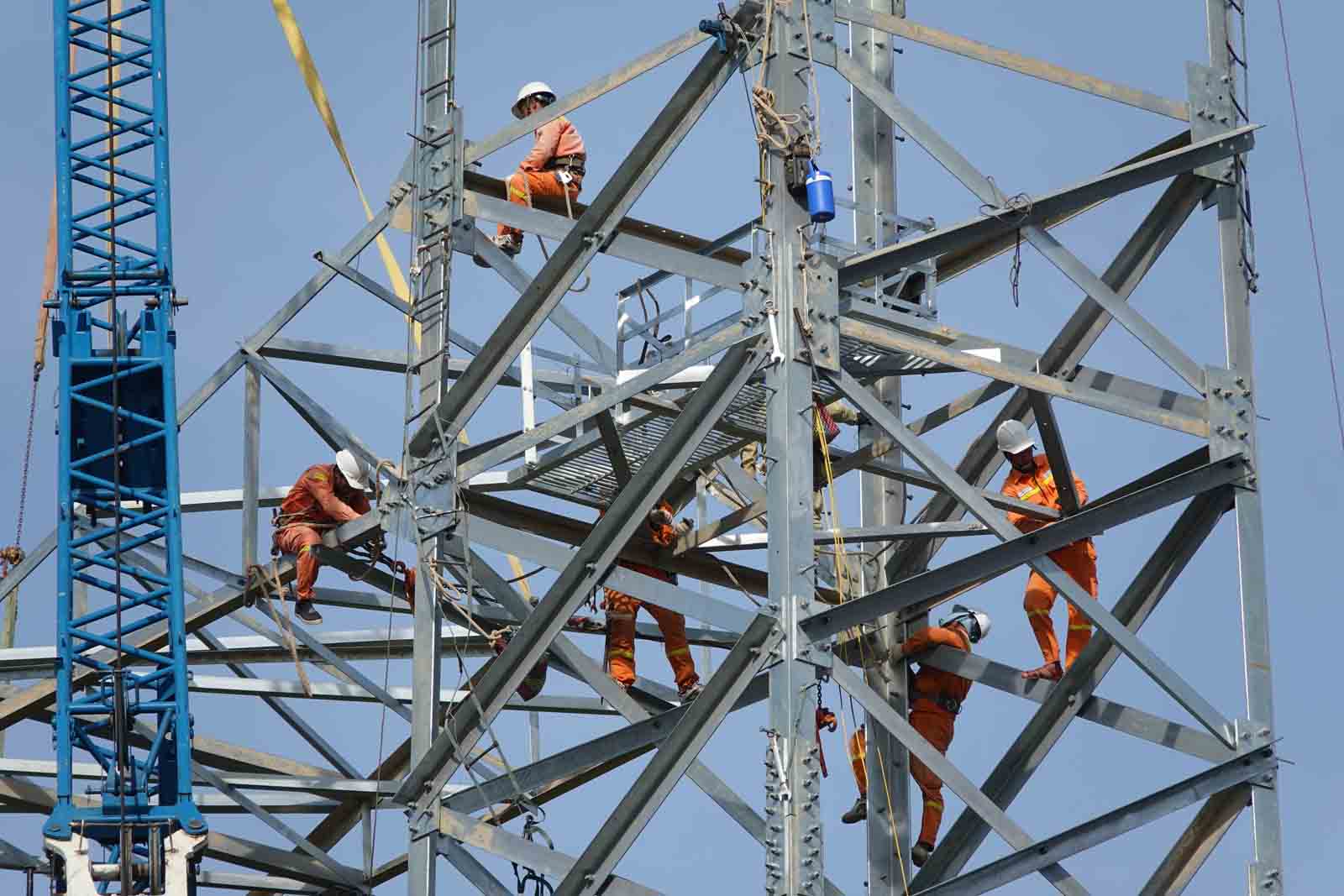 Công nhân Công ty Truyền tải điện Hà Tĩnh tập trung thi công hoàn thành phần lắp dựng đỉnh cột điện số 8 ở xã Kỳ Nam, thị xã Kỳ Anh, tỉnh Hà Tĩnh ngày 20.8. Ảnh: Trần Tuấn