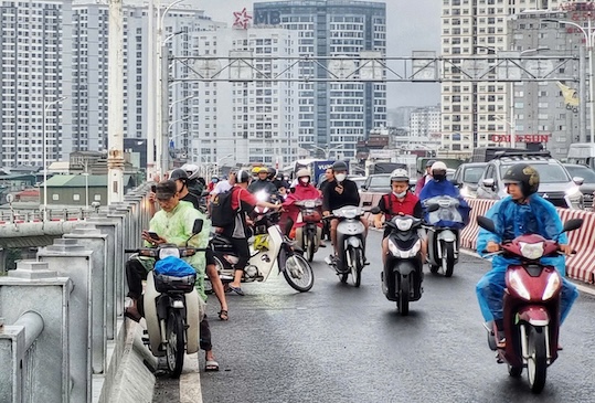 Nhiều người dân đứng trên cầu để theo dõi nước sông Hồng, có thể gây cản trở giao thông và mất an toàn bởi gió trên cầu khá to. Ảnh: Tô Thế. 