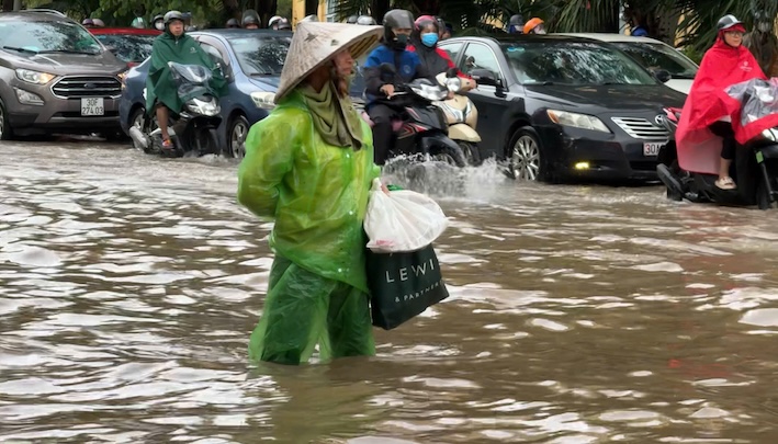 Bà Nguyễn Thị Tình (Đông Anh, Hà Nội) đi làm ở khu vực đường Võ Chí Công (Tây Hồ) bằng xe điện. Hiện nước ngập quá đầu gối, bà Tình phải đón xe bus về nhà, nhưng do nước ngập sâu nên không thể di chuyển. 