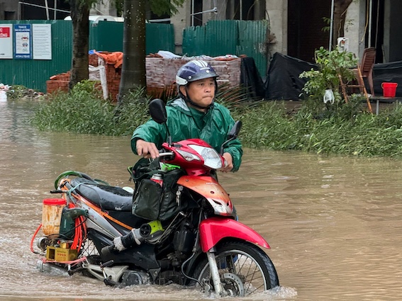 Nhiều chủ phương tiện phải dắt xe lội nước vì xe bị chết máy giữa đường. Anh Hùng (phường Đức Thắng, Bắc Từ Liêm) đến Lotte Mall làm việc nhưng đành đi bộ qua quãng đường vừa ngập vừa tắc. Ảnh: Vũ Linh. 