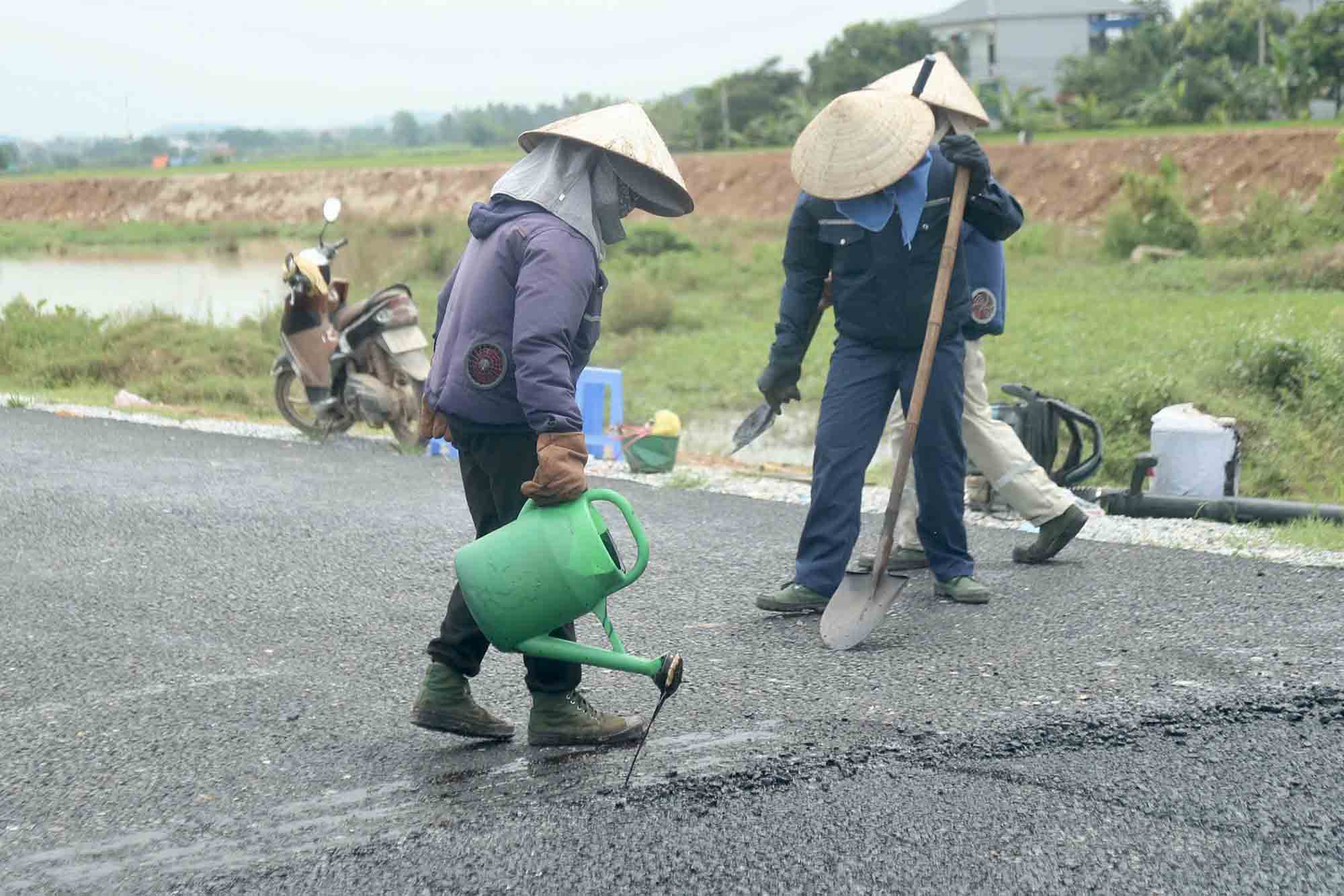 Mỗi ngày đơn vị thi công có thể thảm 200m mặt đường. (Trong ảnh công nhân đang thực hiện quy trình thảm mặt đường).