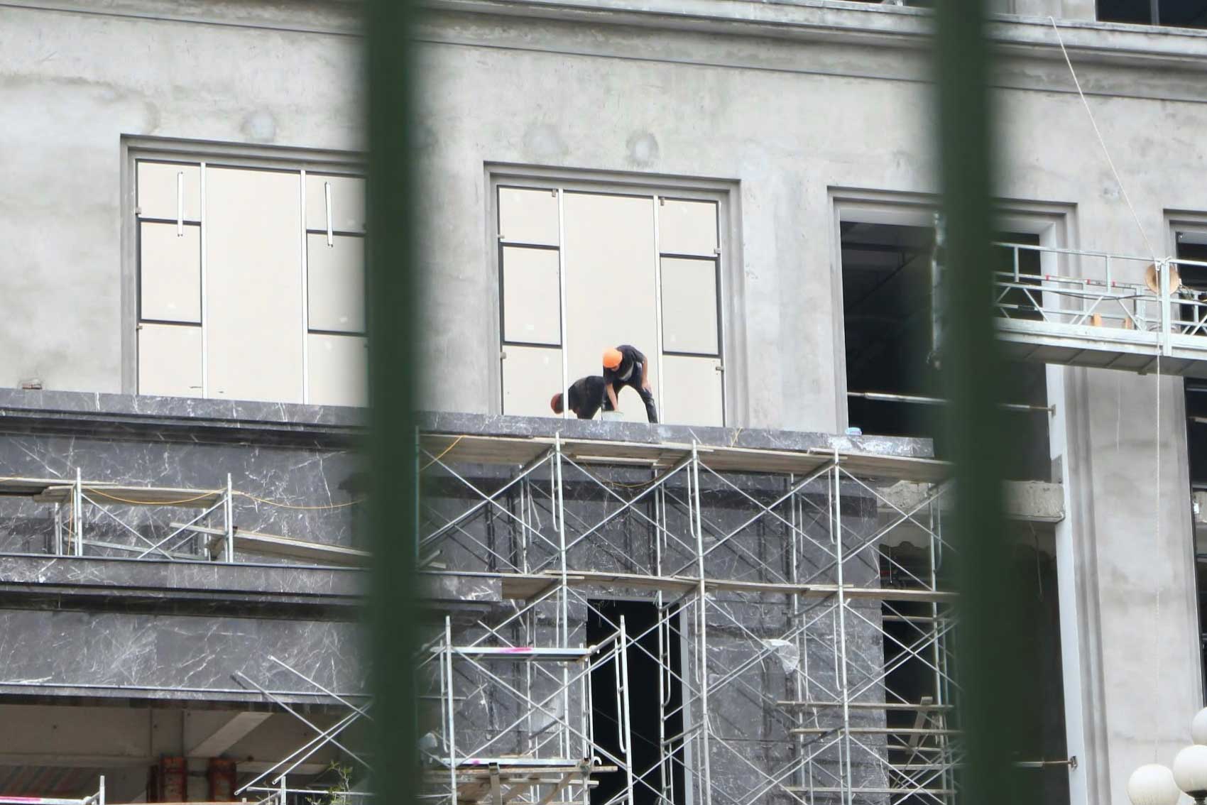 Workers hang themselves to construct project items.