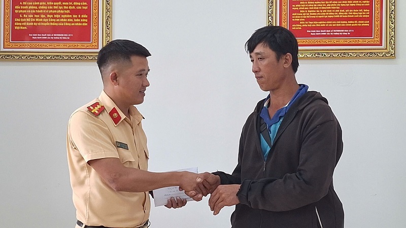 Đại úy Kiều Thanh Hùng (Phòng Cảnh sát giao thông, Công an tỉnh Đắk Lắk) trao trả lại tiền cho ông Phan Ngọc Hùng. Ảnh: Công an cung cấp