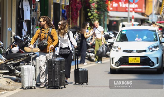 Khách Tây đi bộ dưới lòng đường. Tình trạng chiếm dụng vỉa hè xảy ra ở hầu hết các quận nội thành Hà Nội. Ảnh: Thế Kỷ