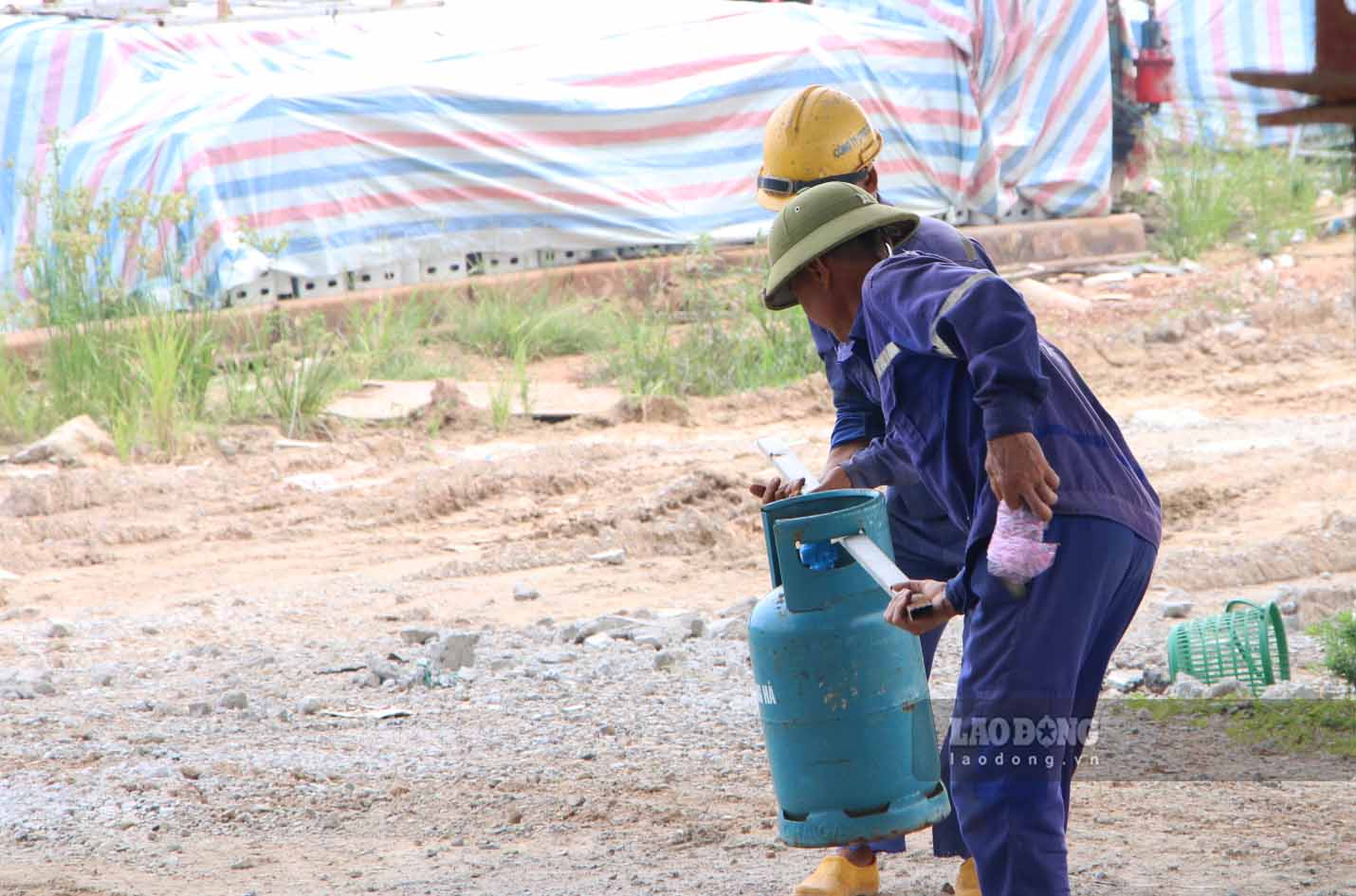 Workers transport gas cylinders to the construction area.