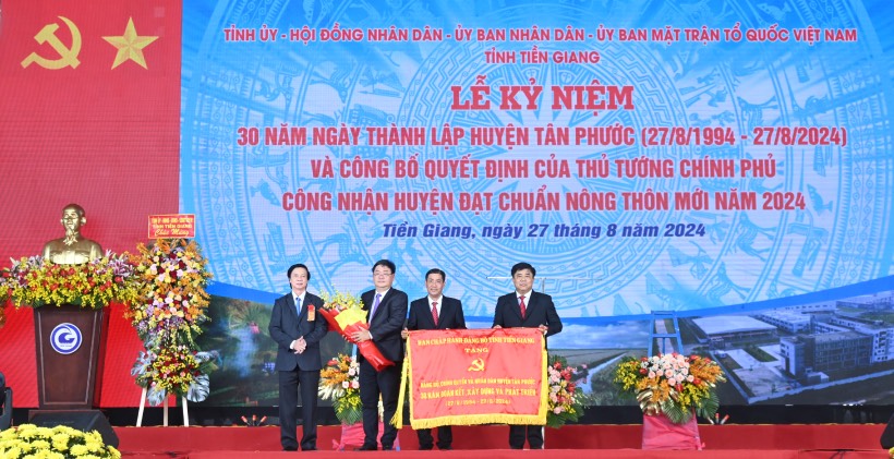 Ông Nguyễn Văn Danh - Bí thư Tỉnh ủy Tiền Giang - trao tặng Bức trướng của Ban Chấp hành Đảng bộ tỉnh Tiền Giang tặng Đảng bộ, chính quyền và nhân dân huyện Tân Phước với dòng chữ “30 năm đoàn kết, xây dựng và phát triển (27-8-1994 - 27-8-2024)“. Ảnh: Thành Nhân