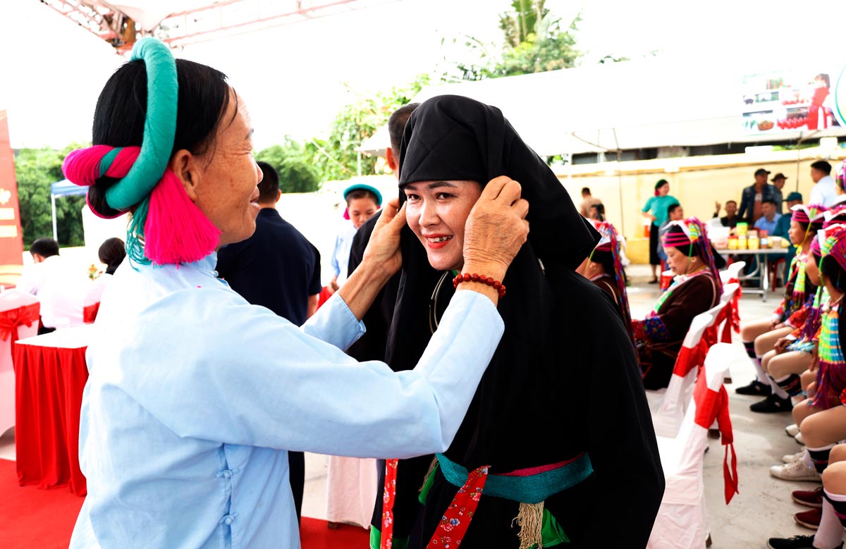 Khách du lịch thử trang phục dân tộc tại phiên chợ Pò Hèn, TP Móng Cái. Ảnh: Cổng TTĐT Móng Cái