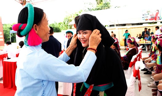 Khách du lịch thử trang phục dân tộc tại phiên chợ Pò Hèn, TP Móng Cái. Ảnh: Cổng TTĐT Móng Cái