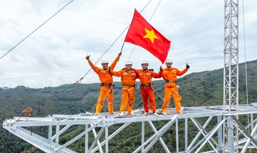 Niềm vui khi hoàn thành xong một vị trí, lá cờ Tổ quốc tung bay trên đỉnh cột đường dây 500kV mạch 3. Ảnh: Thành Vinh