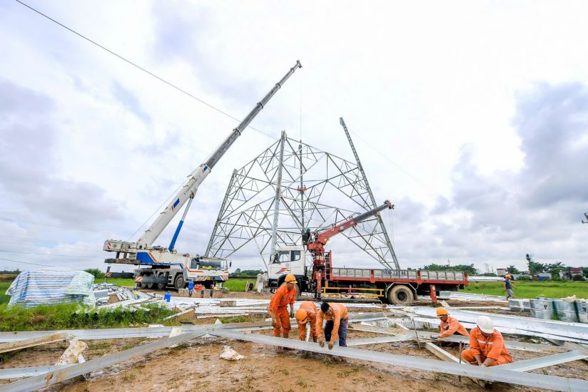 Workers wade through mud to assemble steel bars and use cranes to install them on columns in Nam Duong and Nam Hung communes (Nam Truc district, Nam Dinh province). Photo: Luong Ha