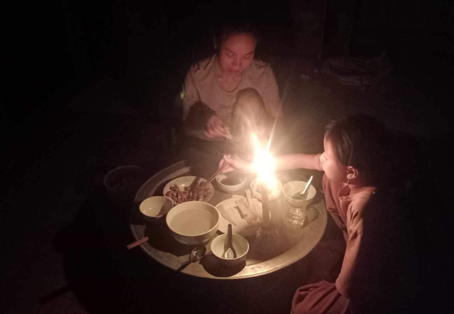 Người dân vùng lũ Chiềng Nơi, Mai Sơn, Sơn La phải thắp nến ăn cơm do mưa lũ khiến cột điện đổ gãy gây mất điện. Ảnh: Cầm Khoa