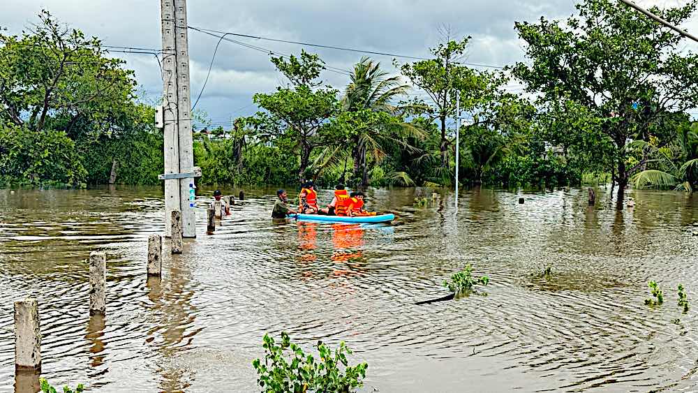 Dùng ván Sup đưa người dân bên trong nhà ngập lên bờ. Ảnh: Duy Tuấn 