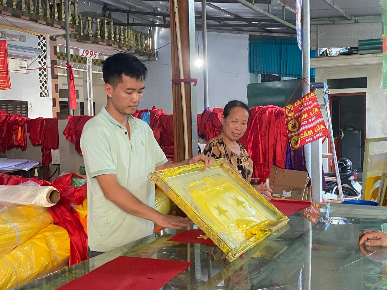 Các nghệ nhân đang thực hiện công đoạn in màu cho lá cờ Tổ quốc. Ảnh: Minh Thương