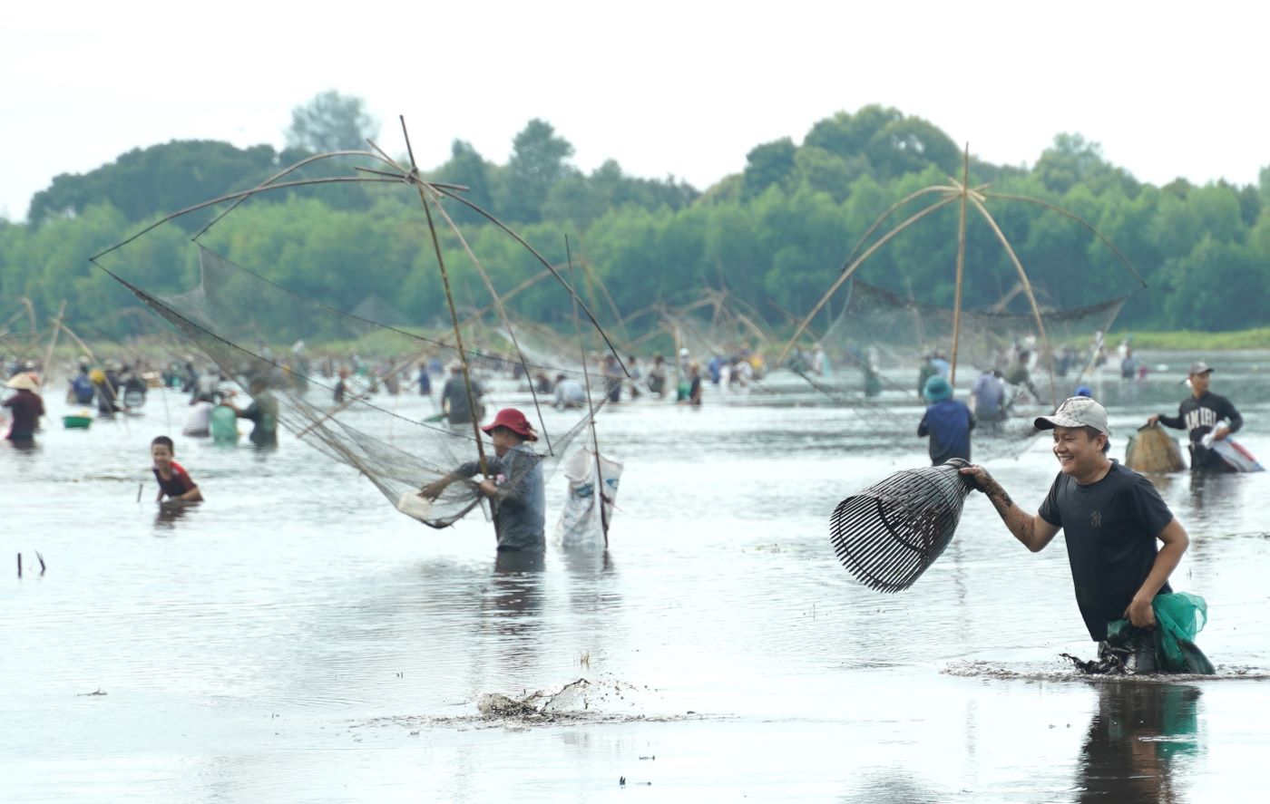 Người đàn ông phát hiện dưới lớp bùn có cá quẫy, liền dùng dụng cụ để đánh bắt.