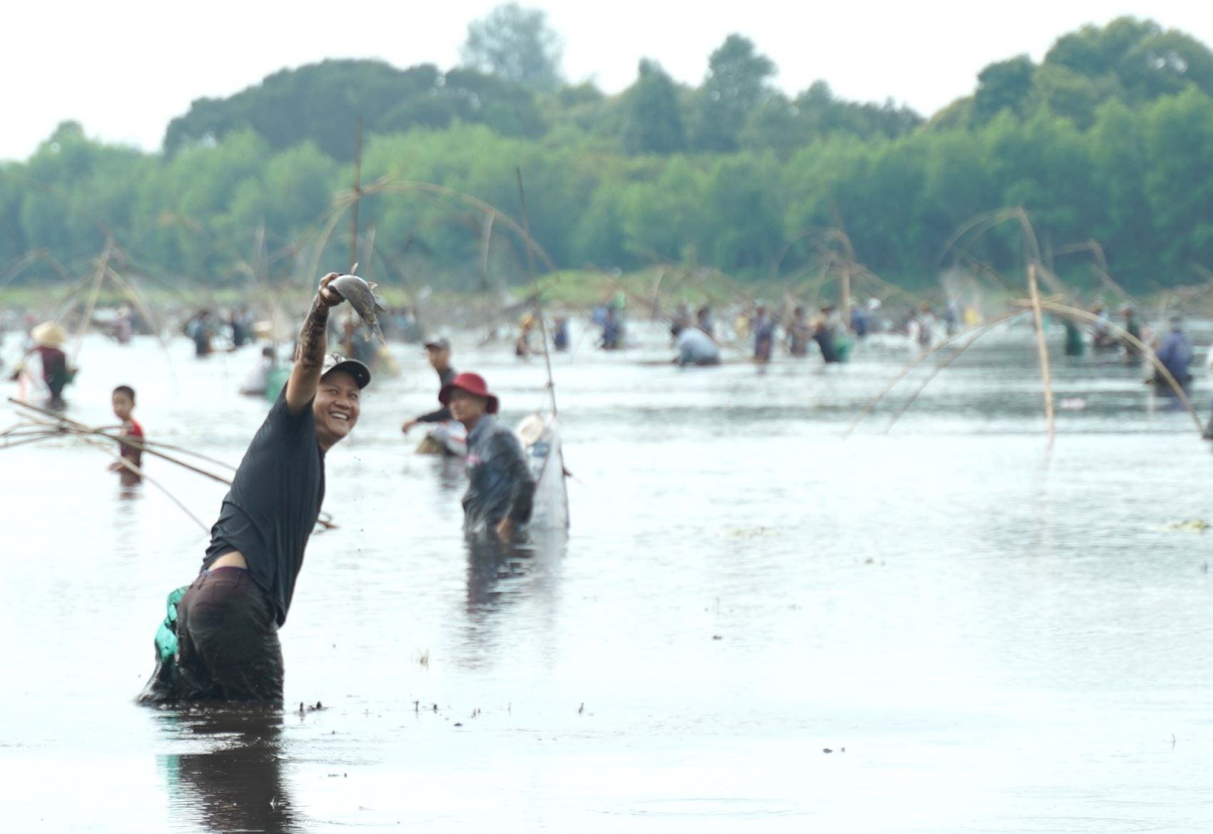 After a few shots, he caught a fish. The man was happy, held the fish up high, and shouted loudly for everyone to join in the fun.