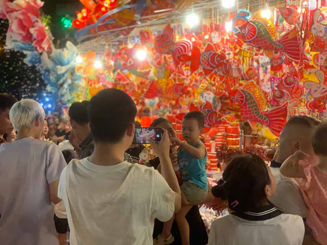 People take pictures next to colorful stalls on Hang Ma Street (Hoan Kiem, Hanoi). Photo: Nhat Minh