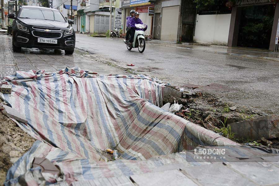 A manhole cover is temporarily covered with a thin tarpaulin.