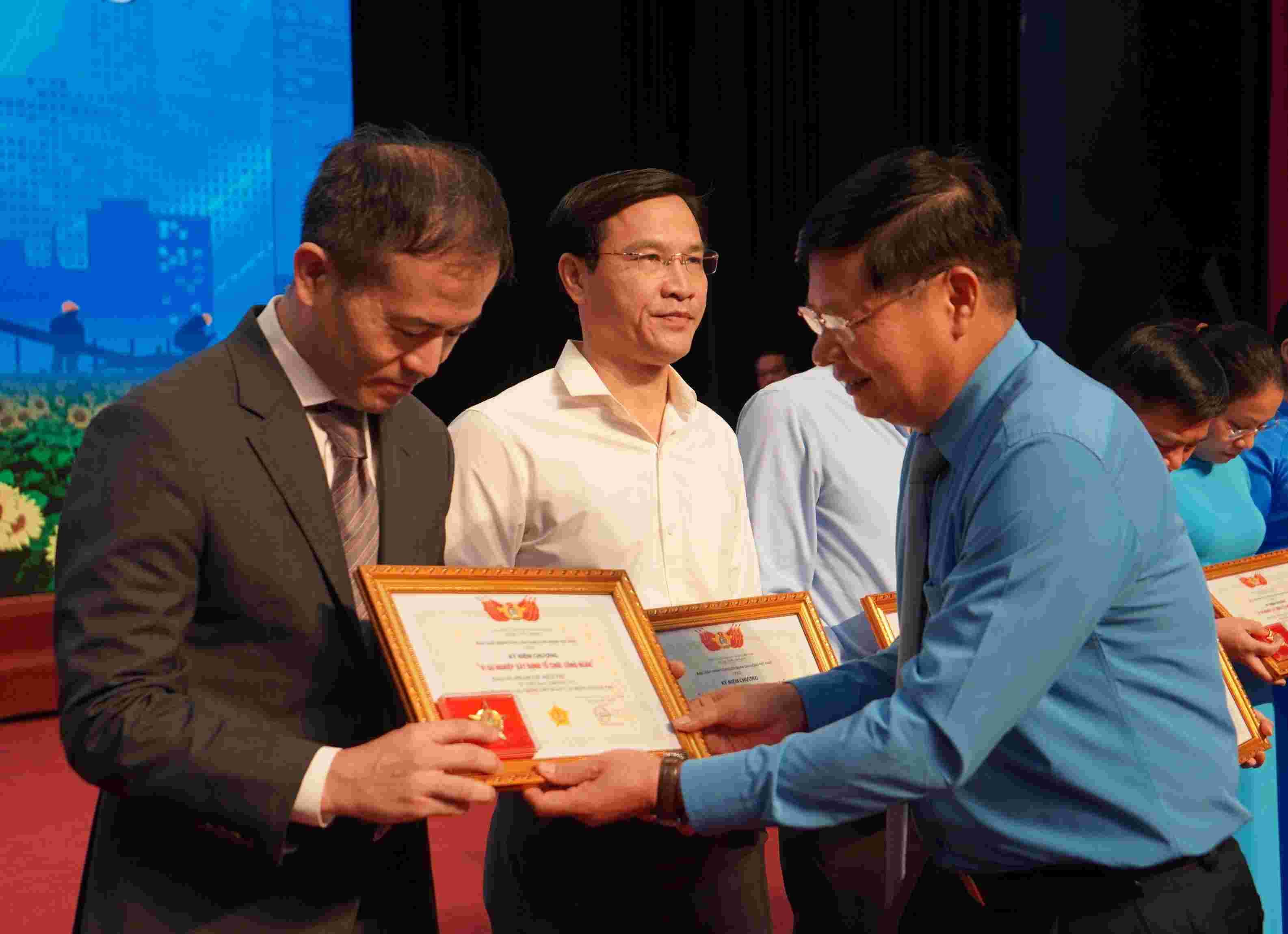 Vice Chairman of the Vietnam General Confederation of Labour Phan Văn Anh presents a commemorative medal 