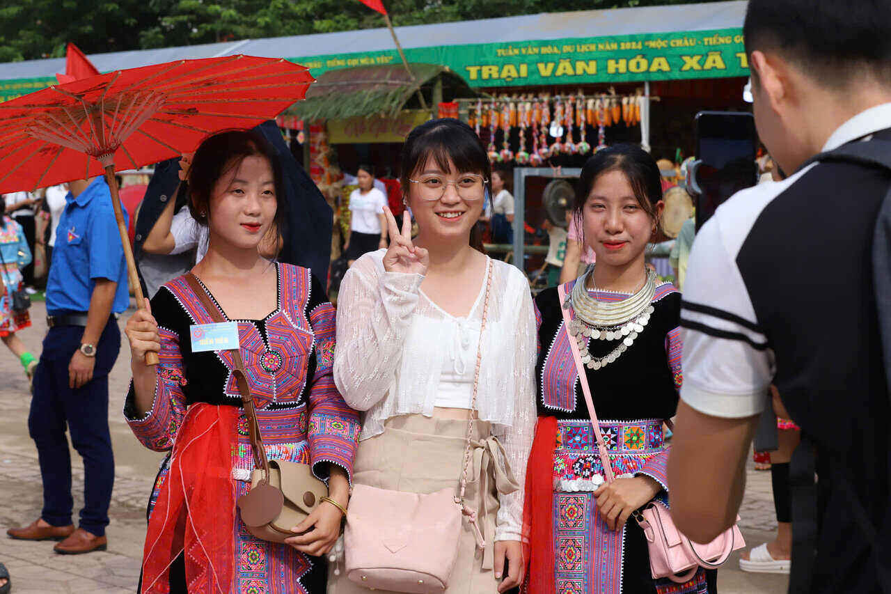 Tourists take souvenir photos with ethnic people in Moc Chau plateau. Photo: Tran Long