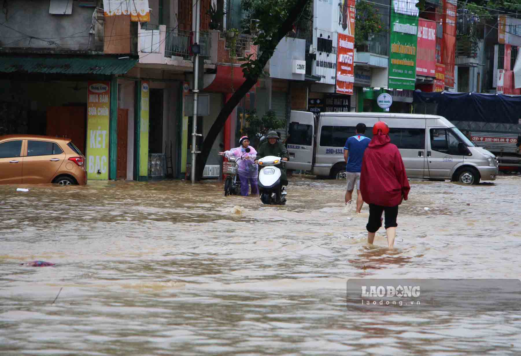 People wade through the water. At 8am this morning, Tuyen Quang Hydropower Plant closed one bottom spillway gate and maintained seven spillways. However, it continues to rain in Tuyen Quang province and the water level of the Lo River is still rising.