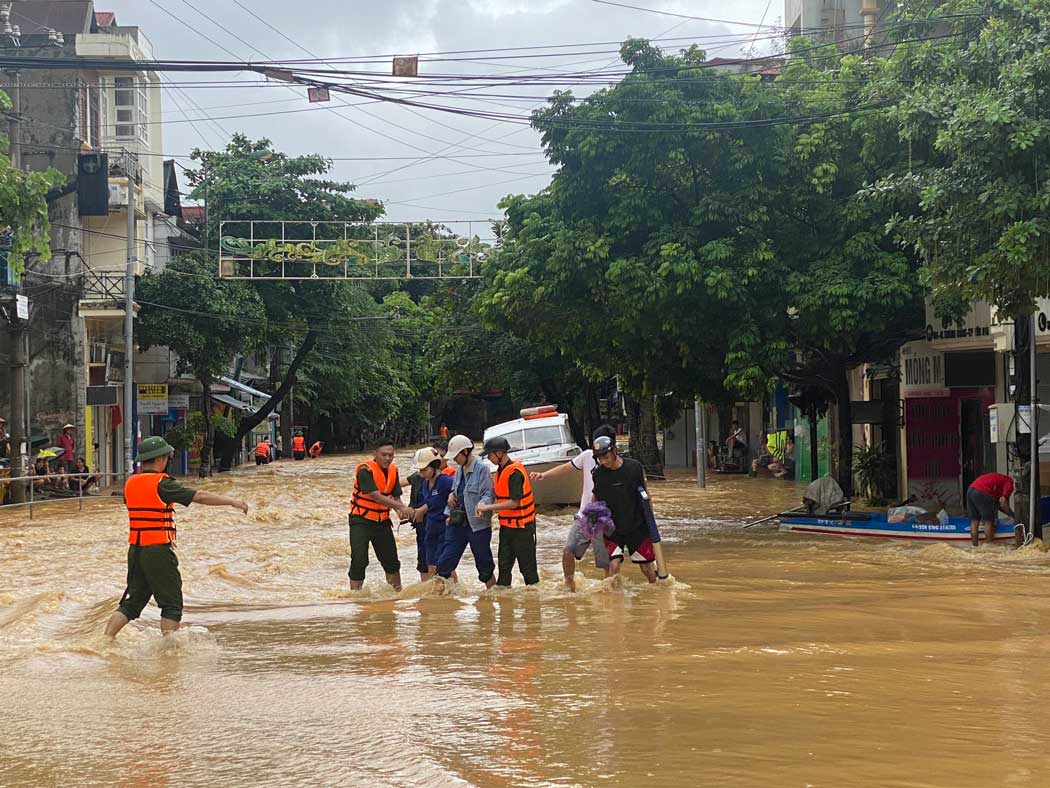 Cán bộ chiến sĩ giúp người dân qua dòng nước siết. Ảnh: Trần Bùi