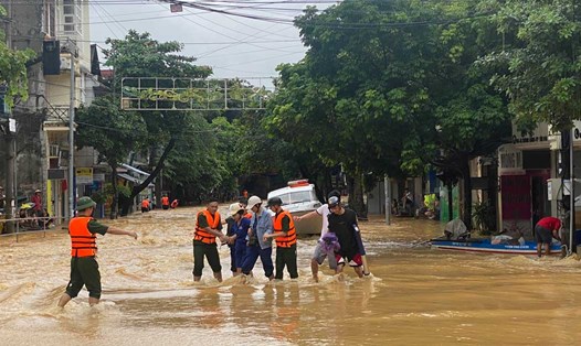 Cán bộ chiến sĩ giúp người dân qua dòng nước siết. Ảnh: Trần Bùi