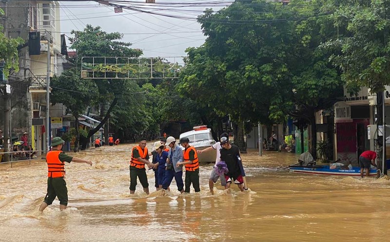 Cán bộ chiến sĩ giúp người dân qua dòng nước siết. Ảnh: Trần Bùi