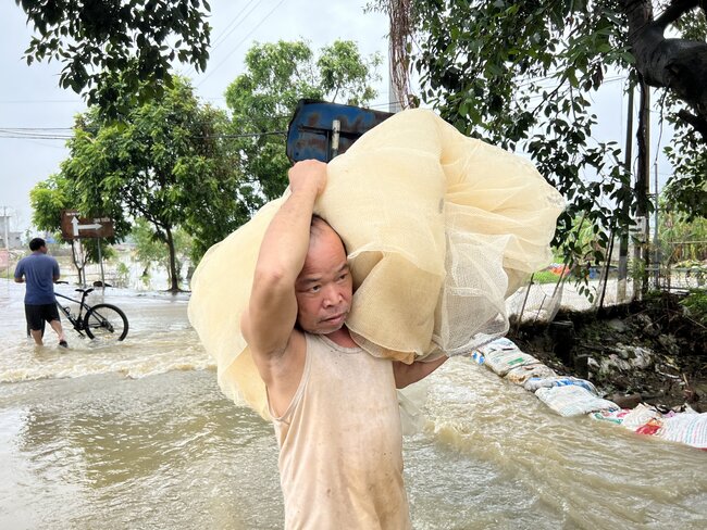 Nước sông Bùi ở huyện Chương Mỹ lên báo động ba và chưa có dấu hiệu dừng lại khiến người dân vội sơ tán tài sản, đắp đập ngăn nước. Ảnh: Cường Ngô