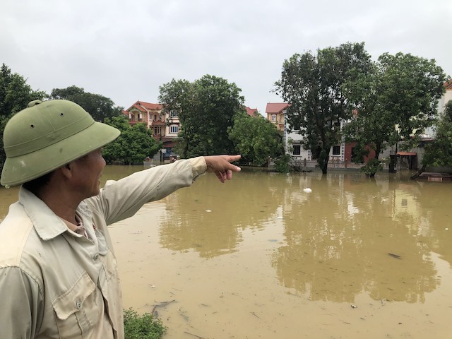 Anh Nguyễn Văn Toàn (thôn Lương Phúc) chỉ tay về ngôi nhà của gia đình mình đang chìm trong nước. 