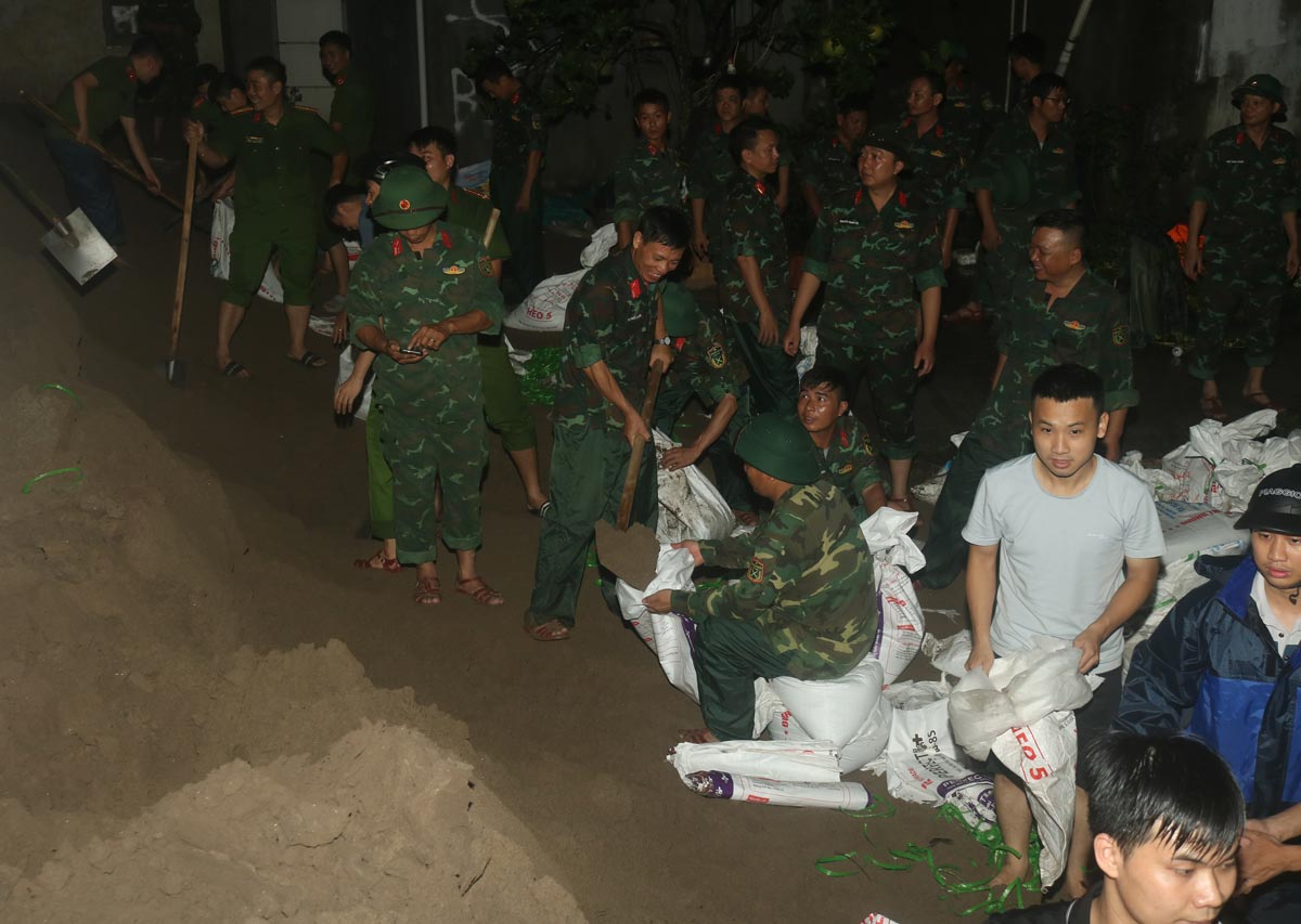 Cán bộ, chiến sĩ Công an TP Nam Định và Ban Chỉ huy Quân sự thành phố cùng người dân hộ đê chống lụt. Ảnh: Phan Nam