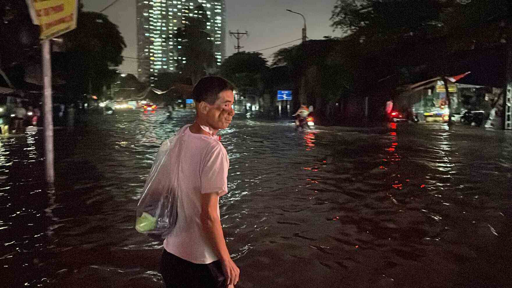 Bệnh nhân Phạm Văn Hoàn (Ninh Bình) bì bõm lội qua vùng nước ngập để đến điều trị tại Bệnh viện K Tân Triều. Ảnh: Thuận Hiền. 