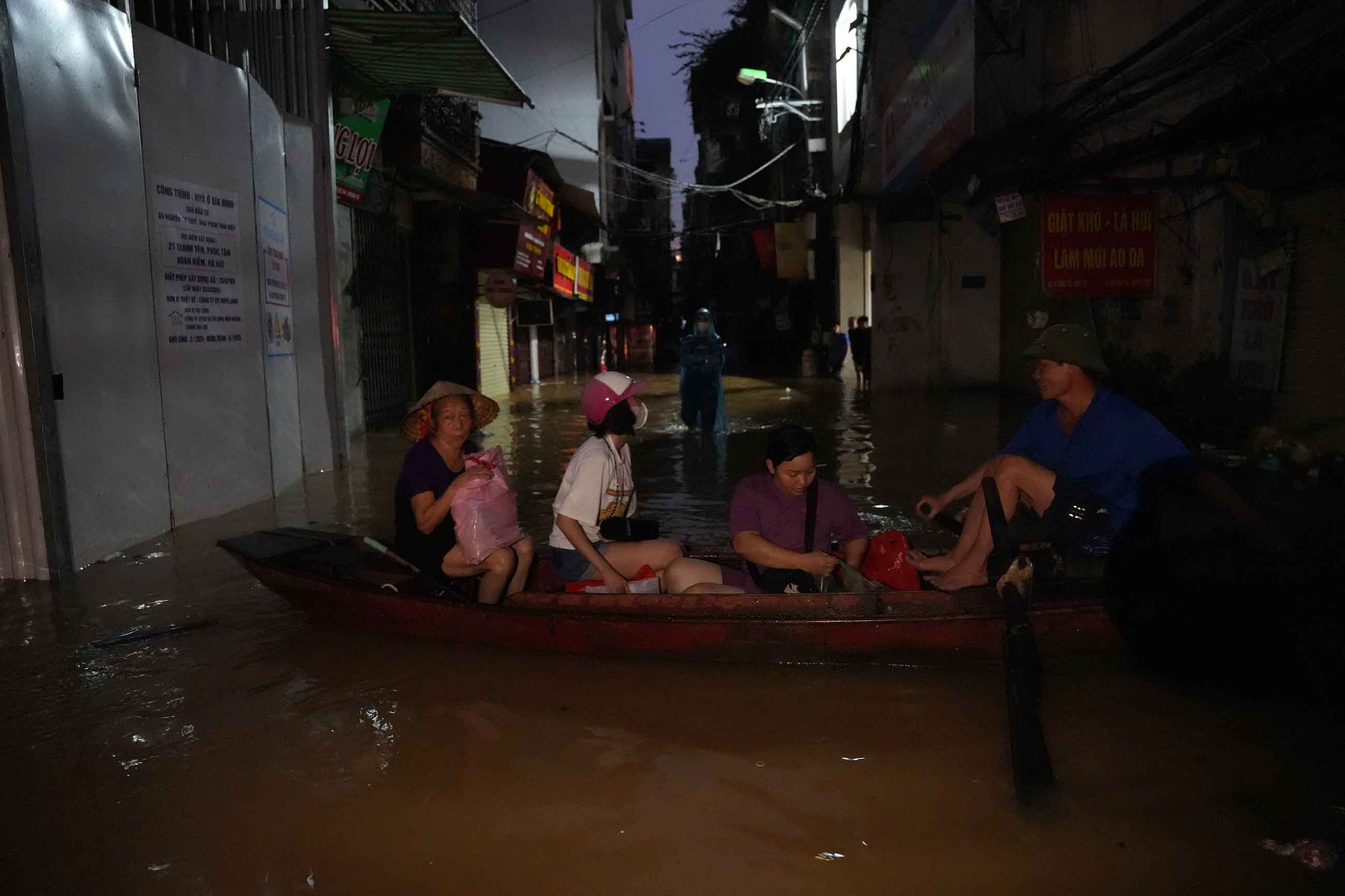 Nhiều hộ dân trên tuyến phố Thanh Yên buộc phải dùng thuyền bè, phao cứu sinh làm phương tiện di chuyển người và đồ đạc trong đêm. Ảnh: Hữu Chánh