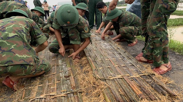 Các chiến sĩ quân đội tham gia đan phên nứa để hộ đê. Ảnh: Đăng Khôi