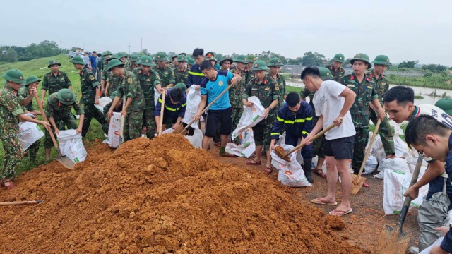 Hơn 200 người thuộc lực lượng quân đội, công an, thị xã và xã Đường Lâm được huy động đến hộ đê. Ảnh: Đăng Khôi