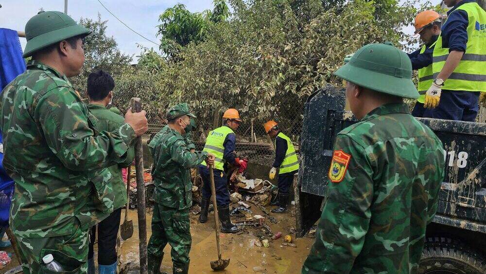 Các lực lượng dọn dẹp bùn cặn, vệ sinh nền đường, thu gom rác, vận chuyển đồ đạc giúp người dân. Ảnh: Việt Bắc