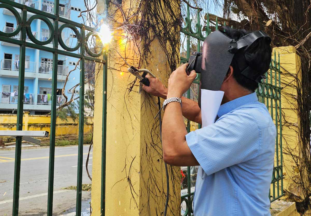 Thầy giáo Trần Văn Sọi - Hiệu trưởng trường Phổ thông Dân tộc nội trú THCS & THPT tỉnh Quảng Ninh hàn lại tường rào bị đổ do bão số 3. Ảnh: Đoàn Hưng