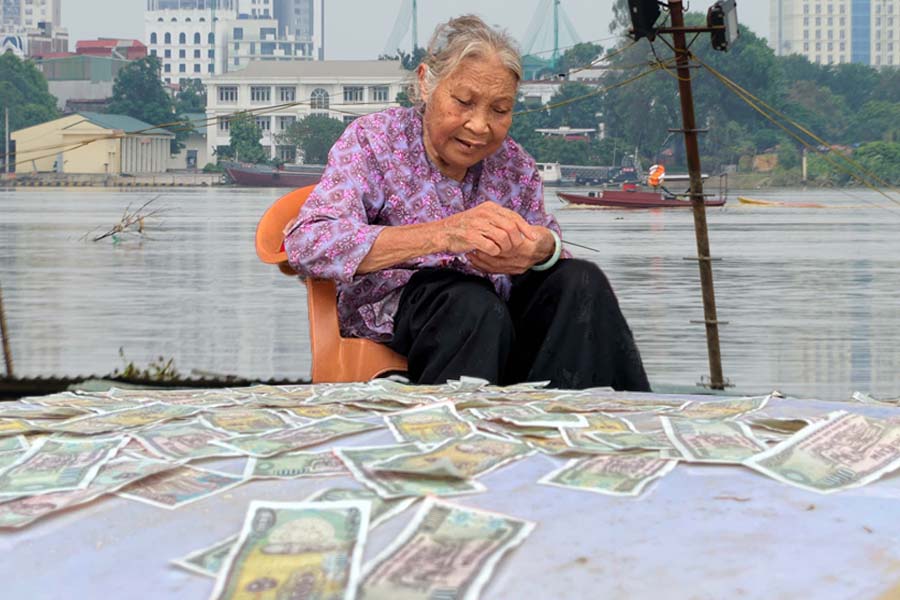 Sau lũ, cụ bà ở Hoàn Kiếm mang tiền lẻ ra phơi.
