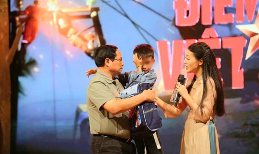 Thủ tướng Chính phủ Phạm Minh Chính động viên, tặng quà cháu Nguyễn Quốc Bảo mồ côi do mưa lũ. Ảnh: Hải Nguyễn