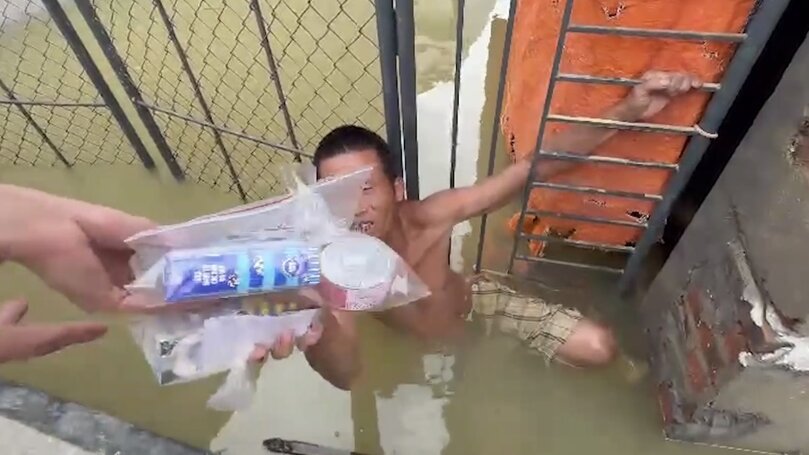 Một người lội nước nhận đồ từ thiện của các nhà hảo tâm. Ảnh: Hoàng Bằng