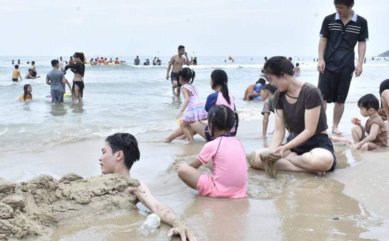 Chị Hoài Thương (áo đen, ngồi) vui chơi cùng gia đình trên bãi biển. Ảnh: Thành An