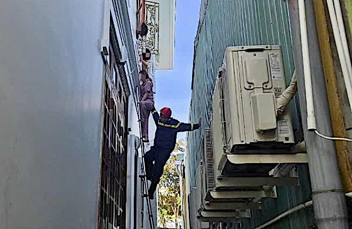 Firefighters brought three people trapped on the upper floor of the burning house down to the ground. Photo: Pham Duy