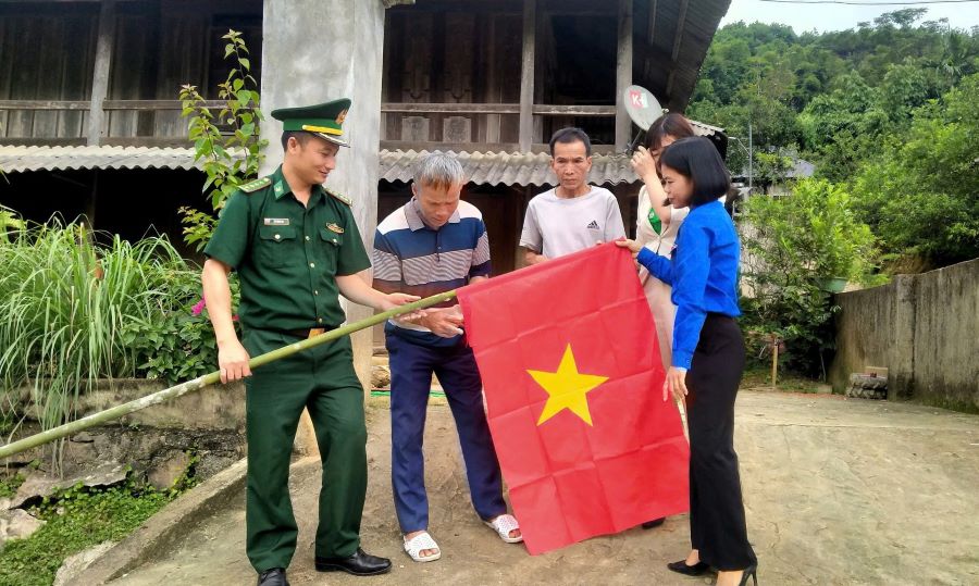 Cán bộ, chiến sĩ Đồn Biên phòng Yên Khương (huyện Lang Chánh) cùng bà con treo cờ Tổ quốc. Ảnh: BPTH