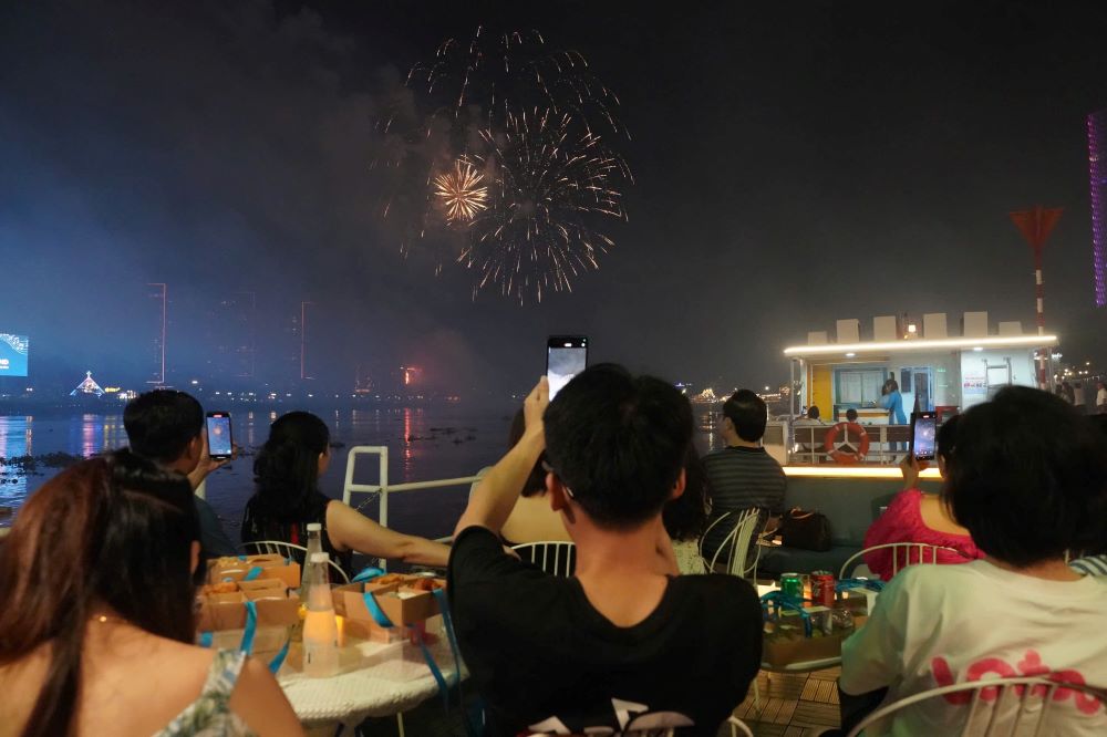 Many people excitedly used their phones to record the moments of fireworks shining brightly in the city sky.